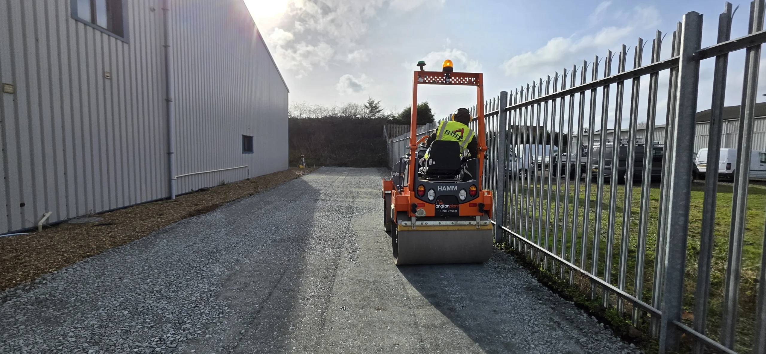 Ride-on roller compacting aggregate on an industrial access road