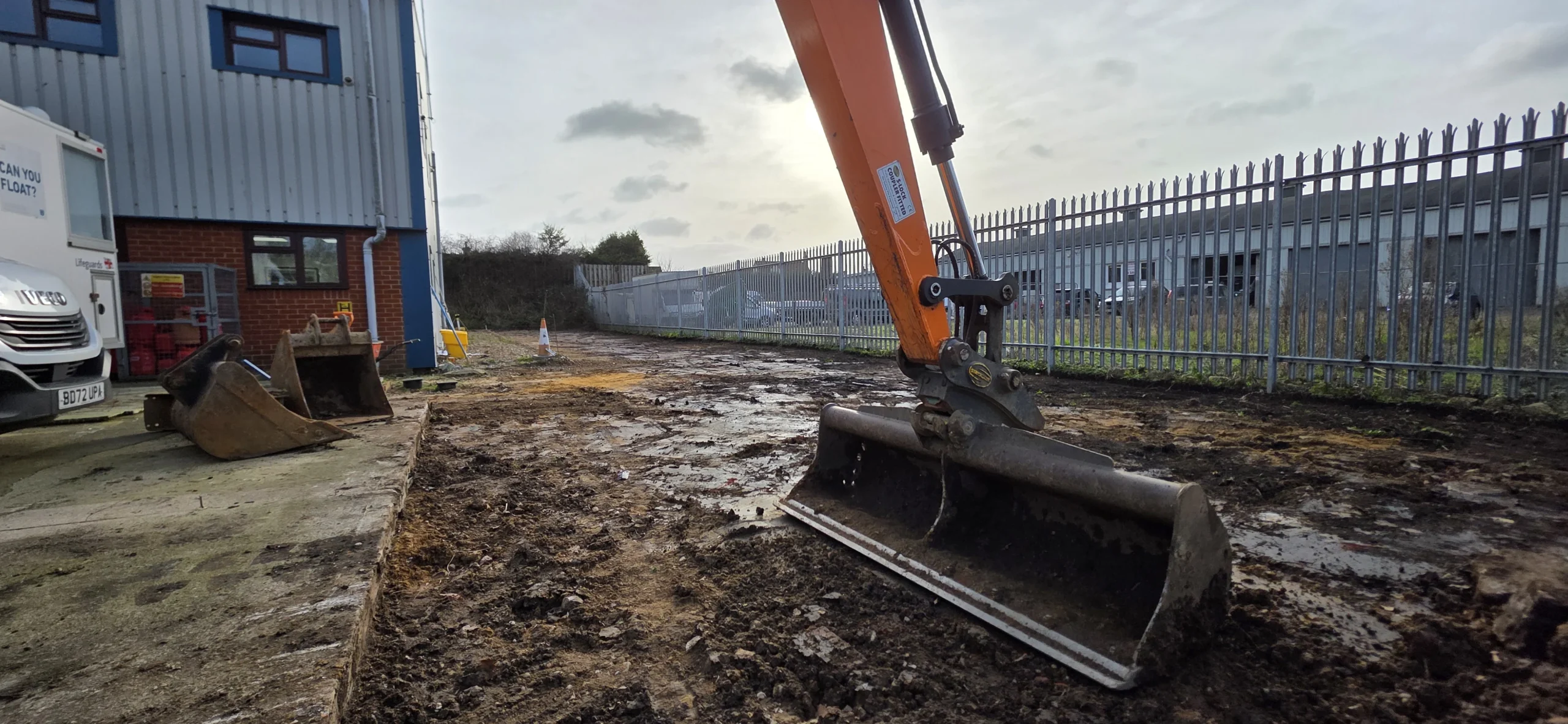 Excavator grading prepared ground for a commercial access road