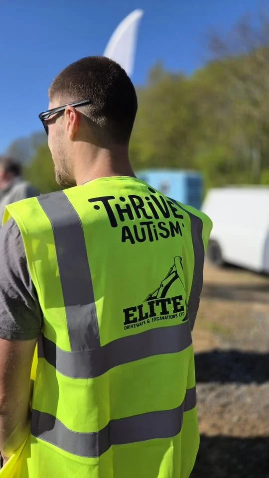 Volunteer wearing a Thrive Autism and Elite Driveways high-visibility vest at Trench Wars